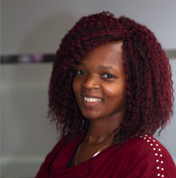black woman with red hair and top smiles at the camera