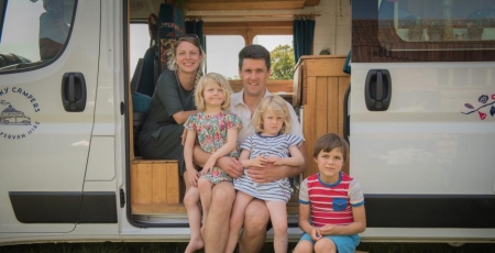 Family of 5 sitting in a van doorway